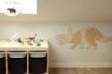 Drewniana dekoracja ścienna dinozaur triceratops w pokoju dziecka obok regału na zabawki