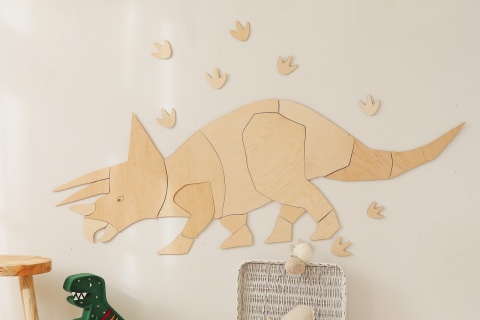 Drewniany triceratops na ścianie w pokoju dziecka nad półką z książkami i zabawkami
