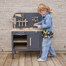 Dziewczynka bawi się drewnianym warsztatem dla dzieci z narzędziami