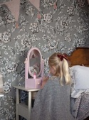 Dziecko bawiące się przy różowej toaletce z lusterkiem w pokoju dziecięcym