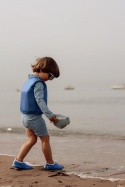 Dziecko w niebieskiej kamizelce do pływania Vanilla Copenhagen podczas zabawy na plaży