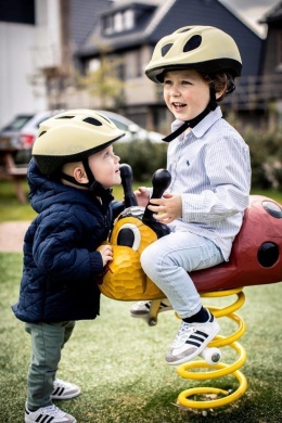 Dzieci w kaskach rowerowych Bobike Lemon podczas zabawy na placu zabaw