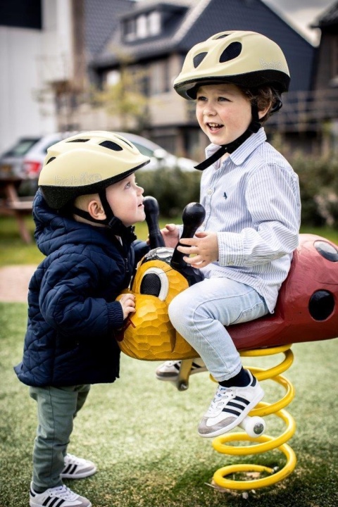 Dzieci w kaskach rowerowych Bobike Lemon podczas zabawy na placu zabaw