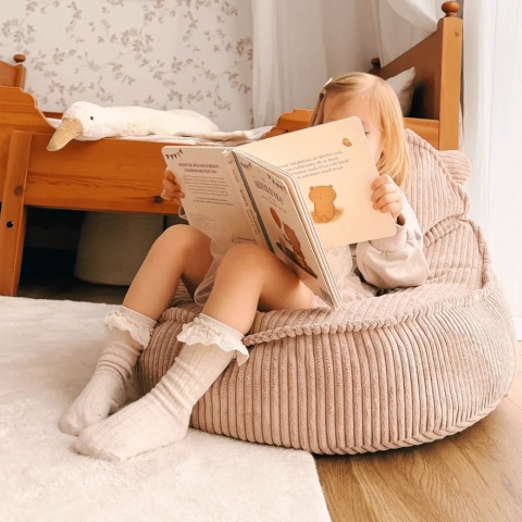 Różowa pufa dla dziecka Teddy Aesthetic w przytulnym pokoju dziecięcym podczas czytania książki