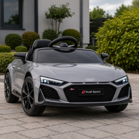 Srebrne Audi R8 na akumulator dla dziecka na podjeździe przed domem – sportowy samochód elektryczny z reflektorami LED