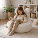 Dziecko siedzące na białej pufie dziecięcej boucle z uszkami misia w pokoju dziecięcym