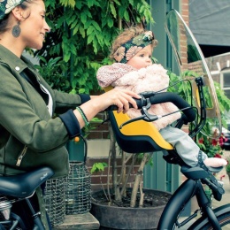 Bobike Mini One Mighty Mustard przedni fotelik rowerowy z osłoną przeciwwiatrową podczas jazdy z dzieckiem