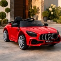 Czerwone auto na akumulator dla dzieci Mercedes GTR na podjeździe przed nowoczesnym domem – samochód elektryczny dla dziecka