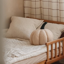 Beżowa poduszka dekoracyjna dynia boucle Soft Loop na łóżku w pokoju dziecka