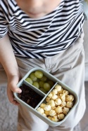 Dziecko trzyma zielony silikonowy lunchbox z trzema przegrodami