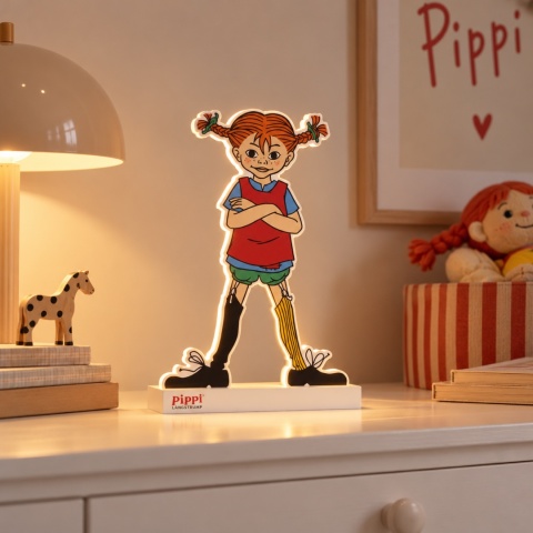 Lampka LED Pippi Pończoszanka o wysokości 35 cm z ciepłym białym podświetleniem, ustawiona na jasnej komodzie