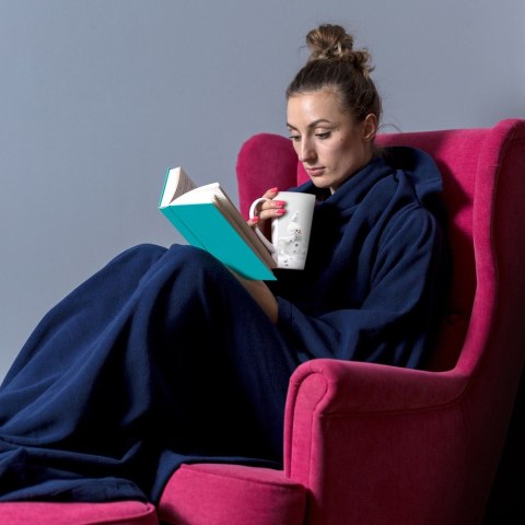 Kobieta w granatowej bluzie kocu z rękawami siedząca w fotelu i czytająca książkę - ciepła bluza oversize do domu